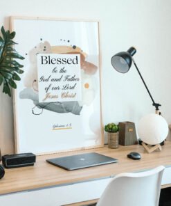 Blessed in faith wall art in a beige frame on the desk with a laptop and a black lamp