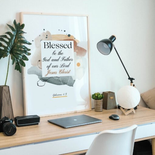 Blessed in faith wall art in a beige frame on the desk with a laptop and a black lamp