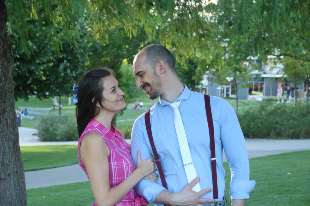 woman wearing pink dress looking at a man in a blue button shirt and a white tie, they look in love