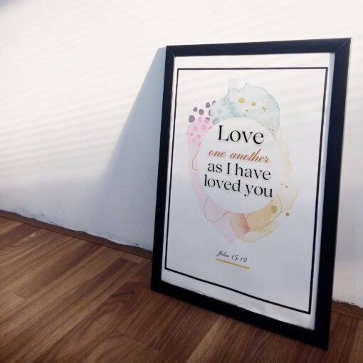 side view of Love One Another Wall Art leaning on a white wall