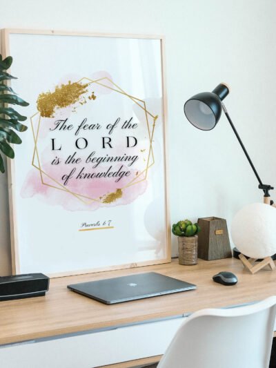 Proverbs 17 Biblical Wall Art placed on a wooden desk naxt to a black lamp