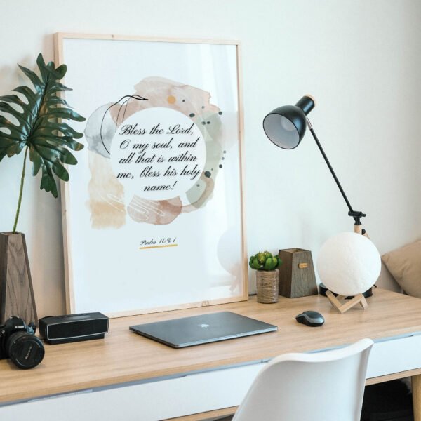 Psalm 103 Wall Art on the wooden desk, next to a black lamp and a laptop