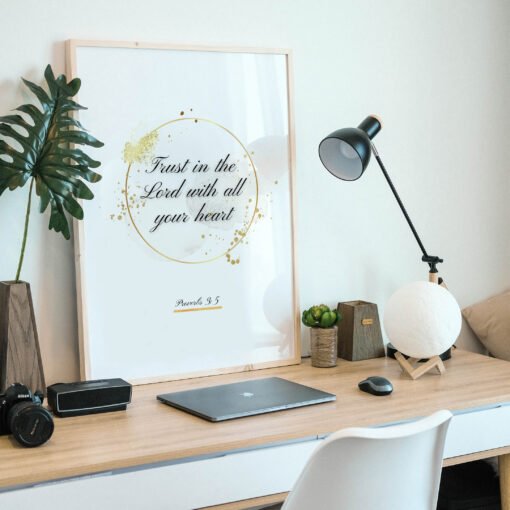 Trust in the Lord Wall Art framed in beige placed on a wooden desk, a plant next to it